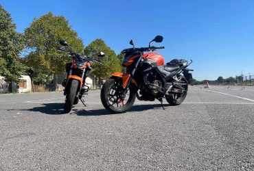 Il y a deux motos oranges sur une piste privée.